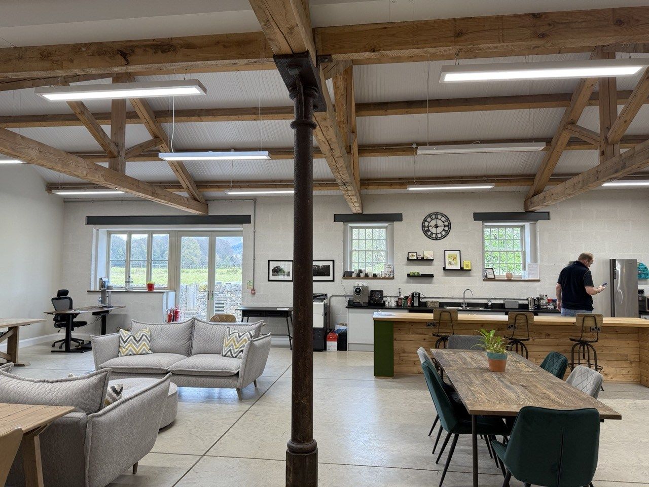 Photo taken from the hotdesk I chose at Herdwork. There are a number of desks, long tables and sofas to sit on. The decor is very clean and light and is a smartly converted barn. There is a kitchen area towards the back of the room.